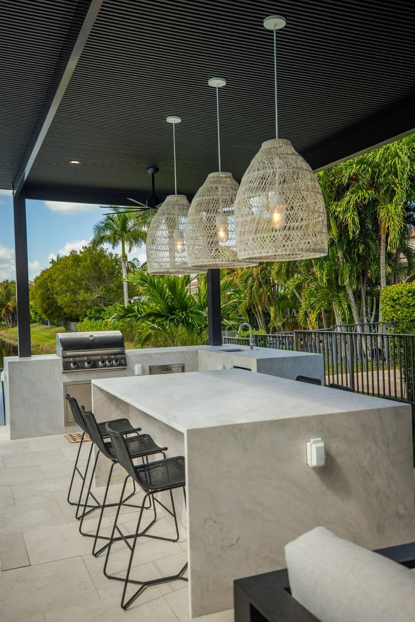 Outdoor kitchen island with stools under a pergola