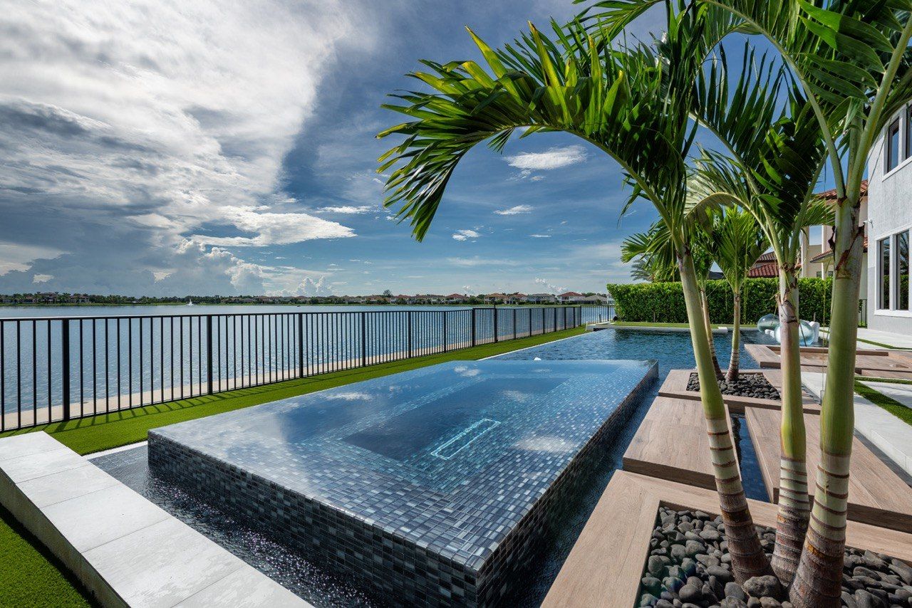Raised spa spilling into the pool with palms and a lake behind